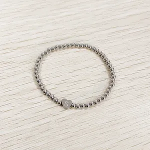 Close-up of stainless steel beaded bracelet with an engraved heart 'S' charm