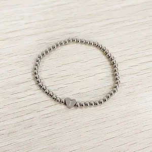 Detailed view of silver stainless steel beaded bracelet with an engraved heart charm