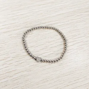 Close-up of heart-shaped 'U' charm on silver stainless steel bead bracelet