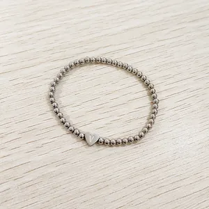 Macro view of stainless steel beaded bracelet with engraved heart initial charm
