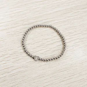 Detail macro view of a silver stainless steel beaded bracelet with an engraved heart initial X charm
