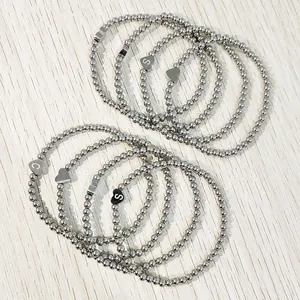 Detailed macro view of several stainless steel bead bracelets with heart initial charms.