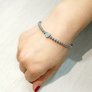 Detailed view of a stainless steel beaded bracelet with a heart 'C' initial charm.
