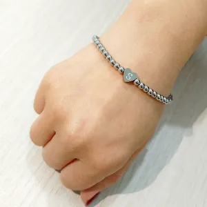 Detail shot of a silver stainless steel beaded bracelet with an engraved heart initial charm S