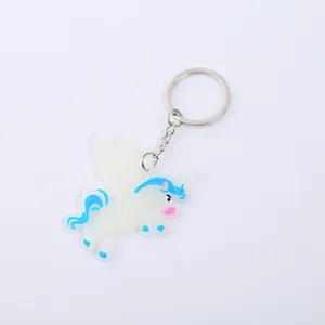 Nahaufnahme eines leuchtenden PVC-Einhorn-Schlüsselanhängers in Weiß und Blau.