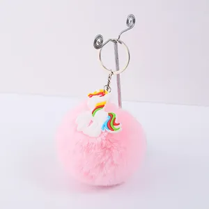 Détail d'un porte-clés pompon rose mignon avec une breloque licorne en PVC colorée