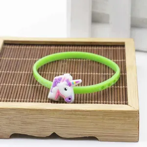 Primo piano di un braccialetto in silicone unicorno verde su un vassoio decorativo in legno