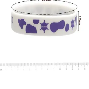 Detail shot of white silicone cowboy wristband with purple sheriff star and cow spots.