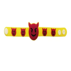 Détail d'un bracelet en silicone jaune avec des imprimés emoji de diable rouge