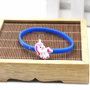 Primo piano di un braccialetto sportivo in silicone blu con un ciondolo a forma di unicorno.