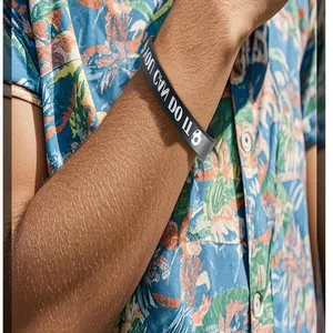 Close-up of a grey silicone sports wristband with soccer motif on a male arm.