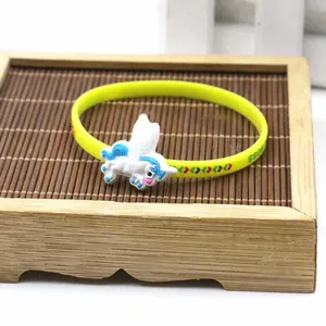 Primo piano di un braccialetto sportivo in silicone giallo con un ciondolo a unicorno