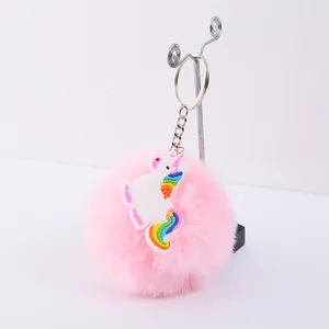 Gros plan d'un porte-clés pompon rose avec charme licorne arc-en-ciel