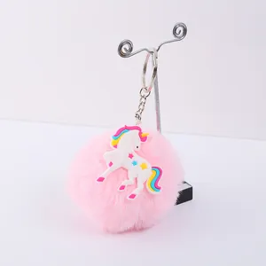 Vue détaillée d'un porte-clés pompon rose duveteux avec un charme licorne en PVC coloré.