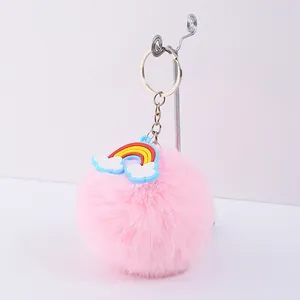 Vue détaillée d'un porte-clés pompon en fausse fourrure rose avec arc-en-ciel