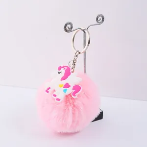 Détail d'un porte-clés en fausse fourrure rose avec une charmante licorne en PVC blanc.