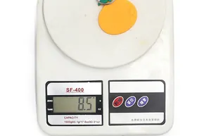 Vue macro d'un porte-clés orange pesé sur une balance numérique indiquant 8,5 grammes