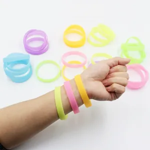 Glow-in-the-dark silicone wristbands shown on a wrist and scattered in various neon colors