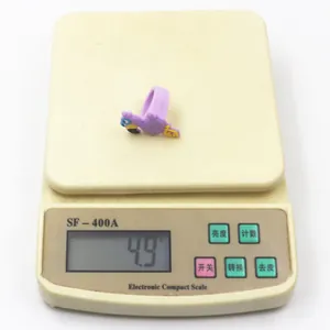 Primo piano di un anello in PVC a fenicottero viola pesato su una bilancia digitale da 4,9g.