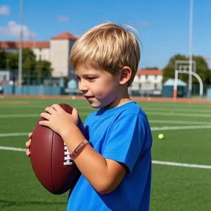 Young boy wearing a brown football-themed silicone wristband on an athletic field