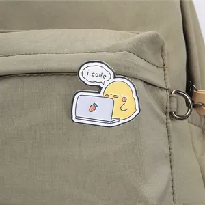 Niedliche Emaille-Brosche mit gelbem Küken 'i code' an einem grünen Rucksack-Detail