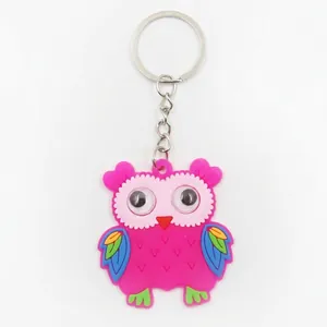 Detail view of a pink PVC owl keychain charm with colorful wings and metal ring.