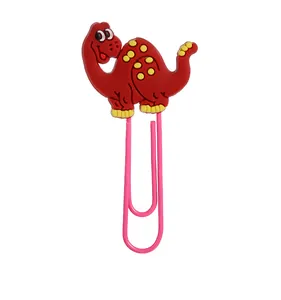 Detail eines niedlichen roten PVC-Dinosauriers an einer rosa Metall-Büroklammer