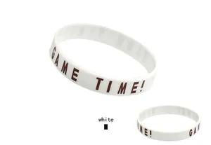 Close-up of white silicone sports wristband with brown GAME TIME! motivational text.