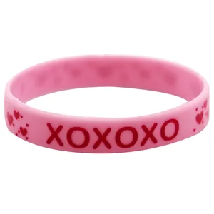 Detailansicht eines rosa Silikonarmbands mit roten XOXOXO Buchstaben und Herzmustern