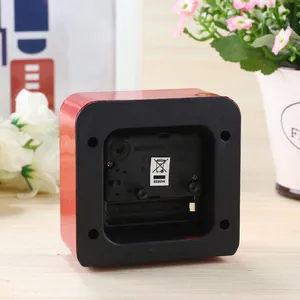 Detailed back view of a simple red alarm clock showing battery compartment and movement