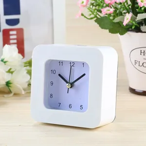 Close-up of a minimalist white square analog desk alarm clock on a wooden surface