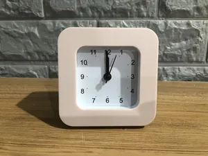 Close-up view of a pink minimalist square analog alarm clock for students and kids