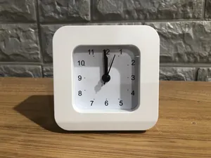 Close-up view of a minimalist white square analog alarm clock for student bedside