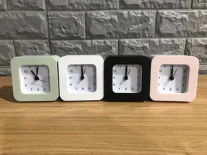Minimalist square alarm clocks in pastel green white black and pink on wood surface