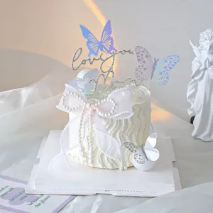 Detailed view of iridescent butterfly toppers and a Love you Mom sign on a cake.