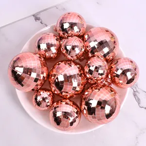 Gros plan de boules à facettes laser or rose de tailles variées sur une assiette blanche