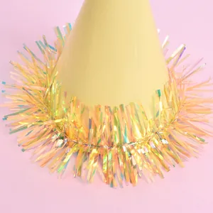 Close-up of mini pet birthday hat featuring iridescent tinsel fringe on pink background.