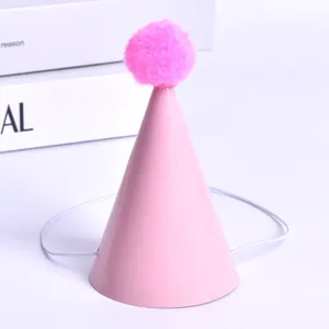 Macro view of a mini pink pet birthday hat with a fuzzy pom-pom and elastic band
