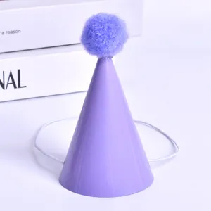 Close-up of mini purple pet party hat with a fluffy purple pom-pom and elastic band.