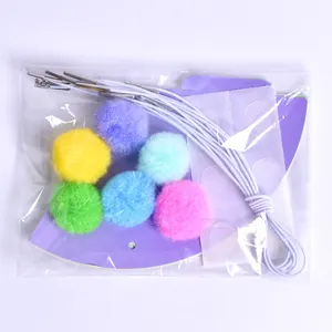 Detailed view of DIY pet birthday hat kit with colorful pom poms and accessories