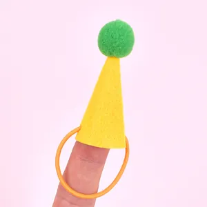 Cute mini yellow felt pet birthday hat with green pom-pom shown on finger for scale