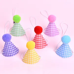 Vue détaillée de chapeaux de fête pour animaux à carreaux colorés avec pompons doux.