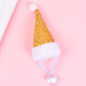 Gros plan d'un bonnet de Noël doré à paillettes pour animaux avec bordure en peluche blanche.