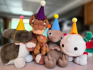 Small colorful felt party hats for pets displayed on various cute stuffed animal toys