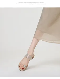 Détail de sandales plates dorées pour femmes avec boucle d'orteil en strass et semelle.