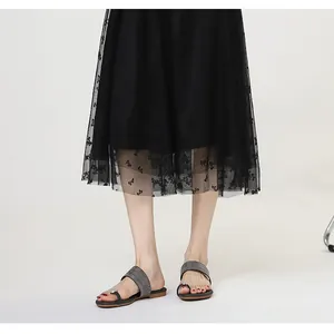 Gros plan de sandales plates avec boucle d'orteil en strass portées avec une jupe en tulle