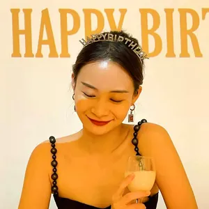 Beautiful Asian woman wearing a sparkling gold Happy Birthday headband at a party