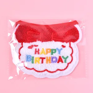Detailed view of plush pet birthday bib with colorful embroidered text in packaging