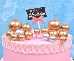 Close-up of golden and silver metallic sphere cake toppers with Happy Birthday flag