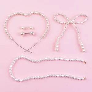 Detail set of pearl heart, bow, and chain cake toppers on a pink background.
